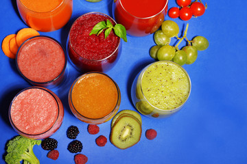 Glasses of tasty fresh juice, on blue background