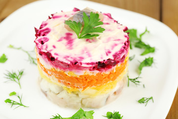 Russian herring salad on plate on wooden table background