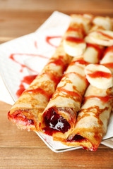 Plate of delicious pancakes with berry jam on wooden background