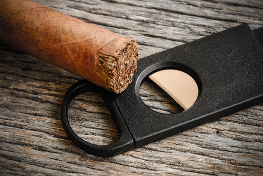 Cigar and Cigar Cutter on Rustic Wood Background