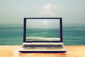 laptop with blank screen over wooden table outdoors
