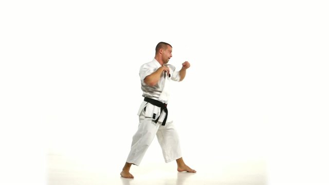 Karate. Man in a kimono hits foot on the white background