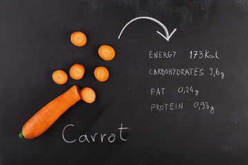 Sliced carrot on  chalkboard  nad written enegry values
