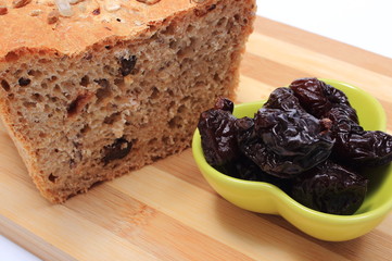 Baked wholemeal bread and heap of dried plums