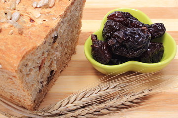Baked wholemeal bread, dried plums and ears of wheat