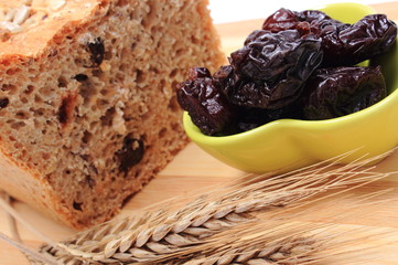 Baked wholemeal bread, dried plums and ears of wheat