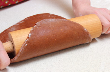 Hands of woman with rolling pin and dough for Christmas cookies