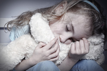 Crying young girl hugging teddy