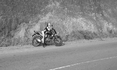Biker theme: beautiful woman with sexy body posing with motorbik