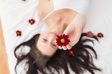 Obraz na płótnie Canvas Pretty brunette posing in bed with flowers