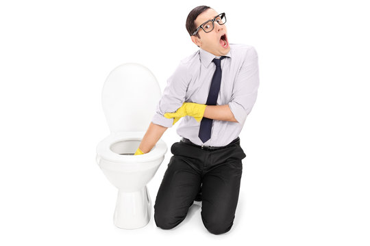 Disgusted man cleaning a toilet with cleaning gloves