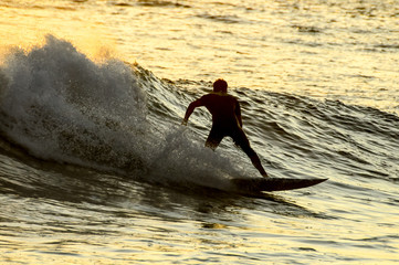 Naklejka premium Sylwetka surfer o zachodzie słońca