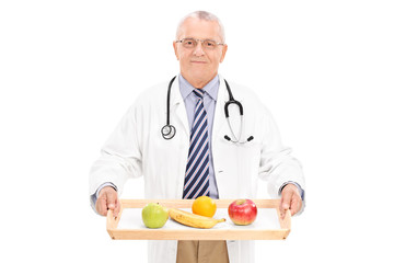 Mature doctor holding tray with a few fruits on it