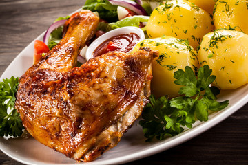 Barbecued chicken leg with boiled potatoes and vegetables