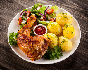 Barbecued chicken leg with boiled potatoes and vegetables