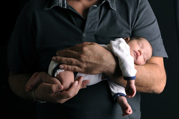 Newborn baby and his father's hand