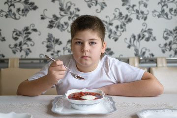 Boy teenager eating soup at  kitchen table