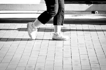 Woman legs walking in sports shoes - monochrome effect