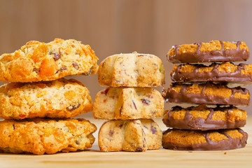 Different cookies in piles on wooden table