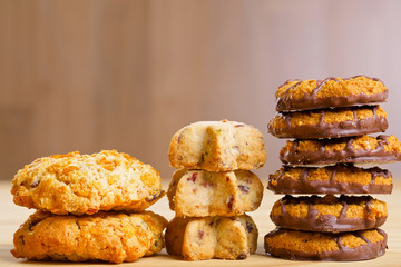 Different cookies in piles on wooden table