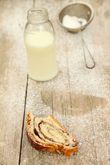 Slice of strudel with bottle of milk on wooden table