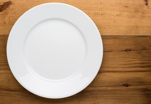 Empty white plate on wooden table