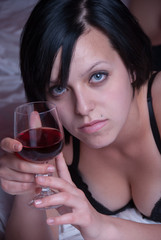 Lady at bed holding a glass of red wine