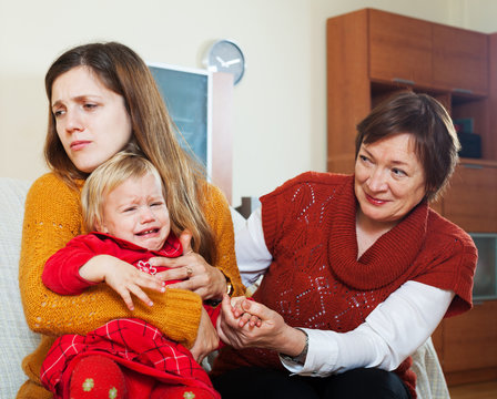 young sadness mother with crying baby and grandmother
