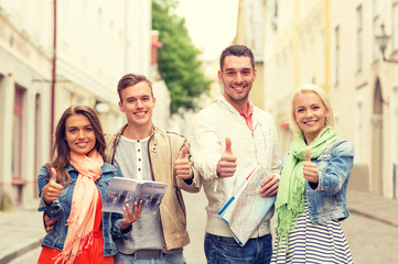 group of smiling friends with city guide and map