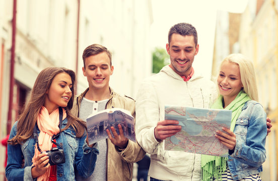 group of friends with city guide, map and camera