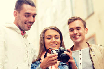 group of smiling friends with digital photocamera