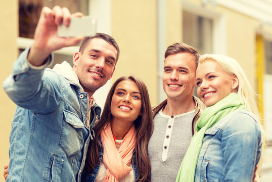 group of smiling friends making selfie outdoors