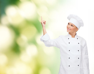 smiling female chef pointing finger to something