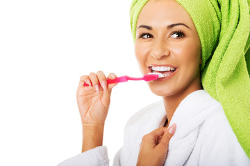 Portrait of a woman in bathrobe brushing teeth