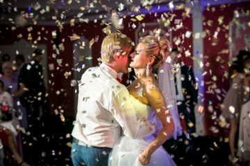 Fototapeta na wymiar portrait of confetti flying at dancing beautiful bride and groom