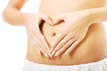 Close up female making heart shape on belly