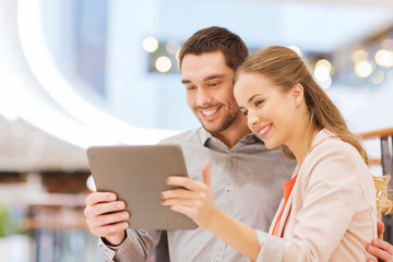 happy couple with tablet pc taking selfie in mall