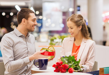 happy couple with present and flowers in mall