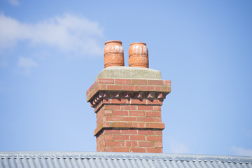 Red brick chimney on roof blue sky copy space