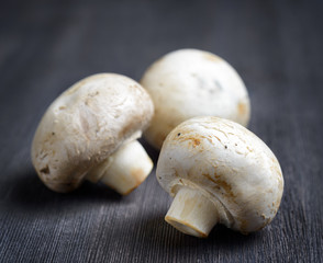 Fresh champignons on black wooden board