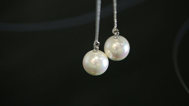 Silver earrings with pearls on a black background