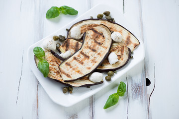 Plate with grilled aubergines, capers and mozzarella, close-up