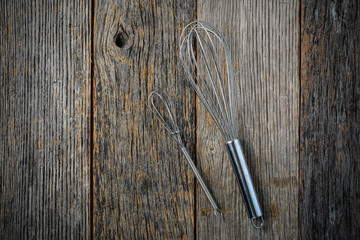 Metal Whisk on Rustic Wood Background