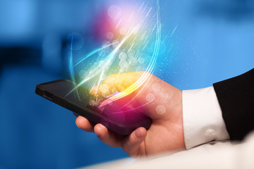 Hand holding smart phone with abstract glowing lines