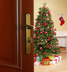 Open door with decorated Christmas tree in room