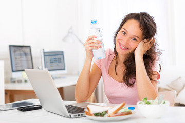 Young attractive student drinking water while working