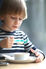 Portrait of a beautiful boy eating with a spoon