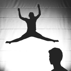 silhouetted gymnast jumping on trampoline