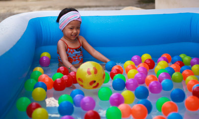 Obraz premium Little girl playing ball in the kiddie pool.