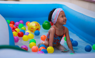 Fototapeta na wymiar Little girl playing ball in the kiddie pool.